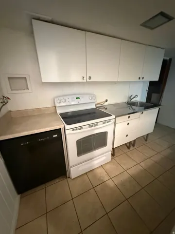 Kitchen area with white cabinetry, a white electric range, a stainless steel sink, black dishwasher, and tile flooring