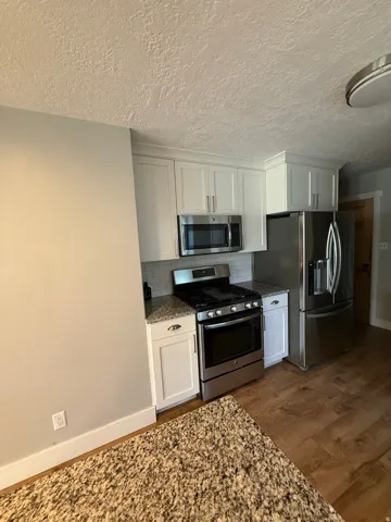Kitchen featuring white shaker cabinetry, stainless steel appliances, speckled countertops, and a subway tile backsplash