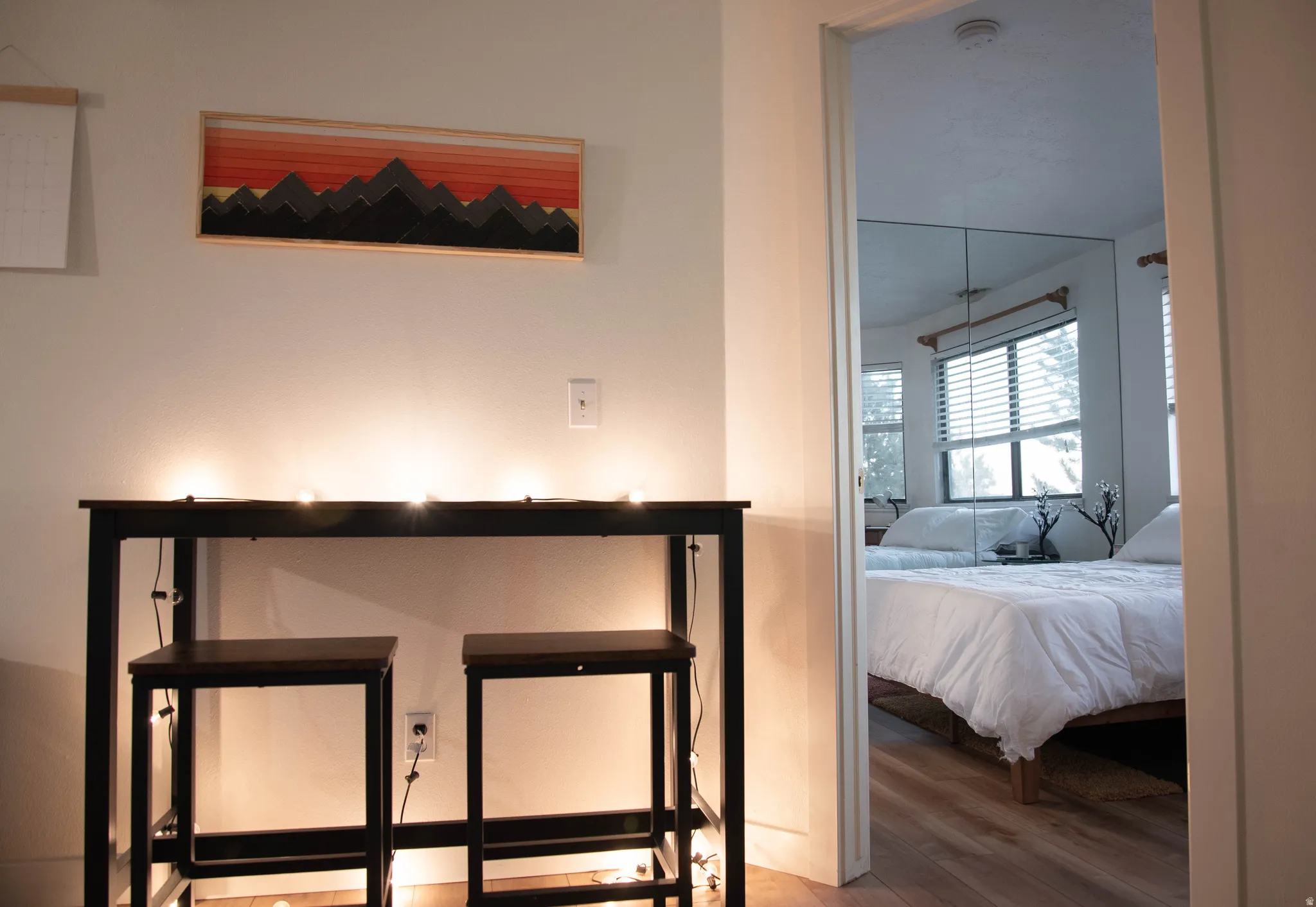 Bedroom with wood-finish flooring and a mirror-paneled wall