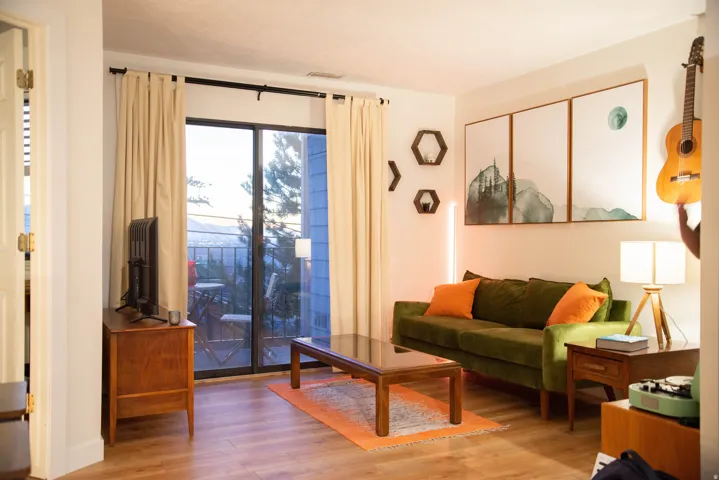 Living area featuring wood-finish flooring, a full-light glass sliding door to a balcony, and white painted walls