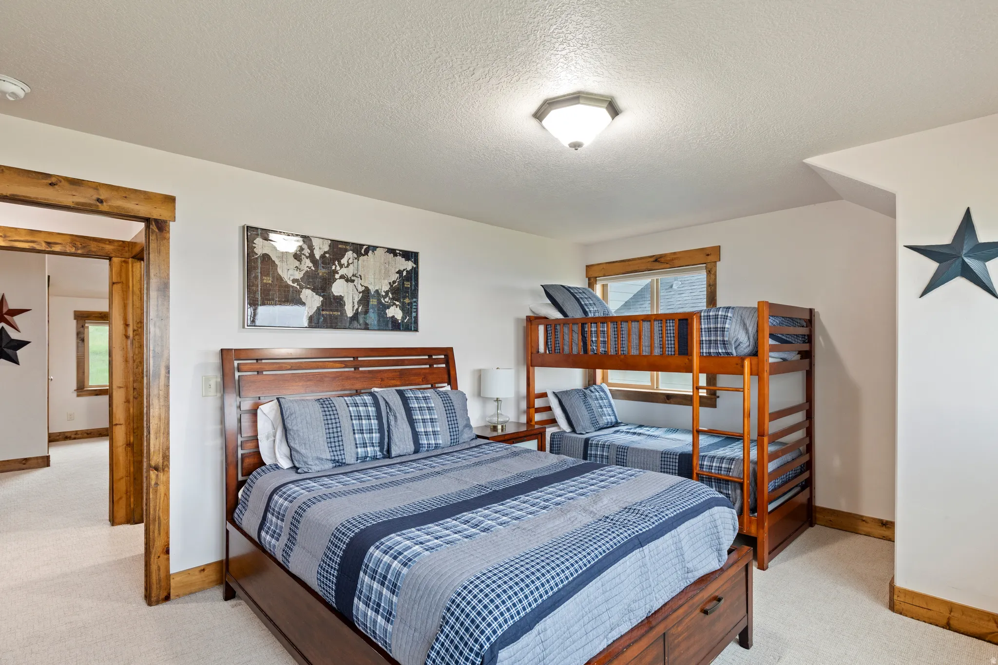 Carpeted room featuring a wooden bed frame, a wooden bunk bed, a window with wooden trim, and a doorway with wooden trim