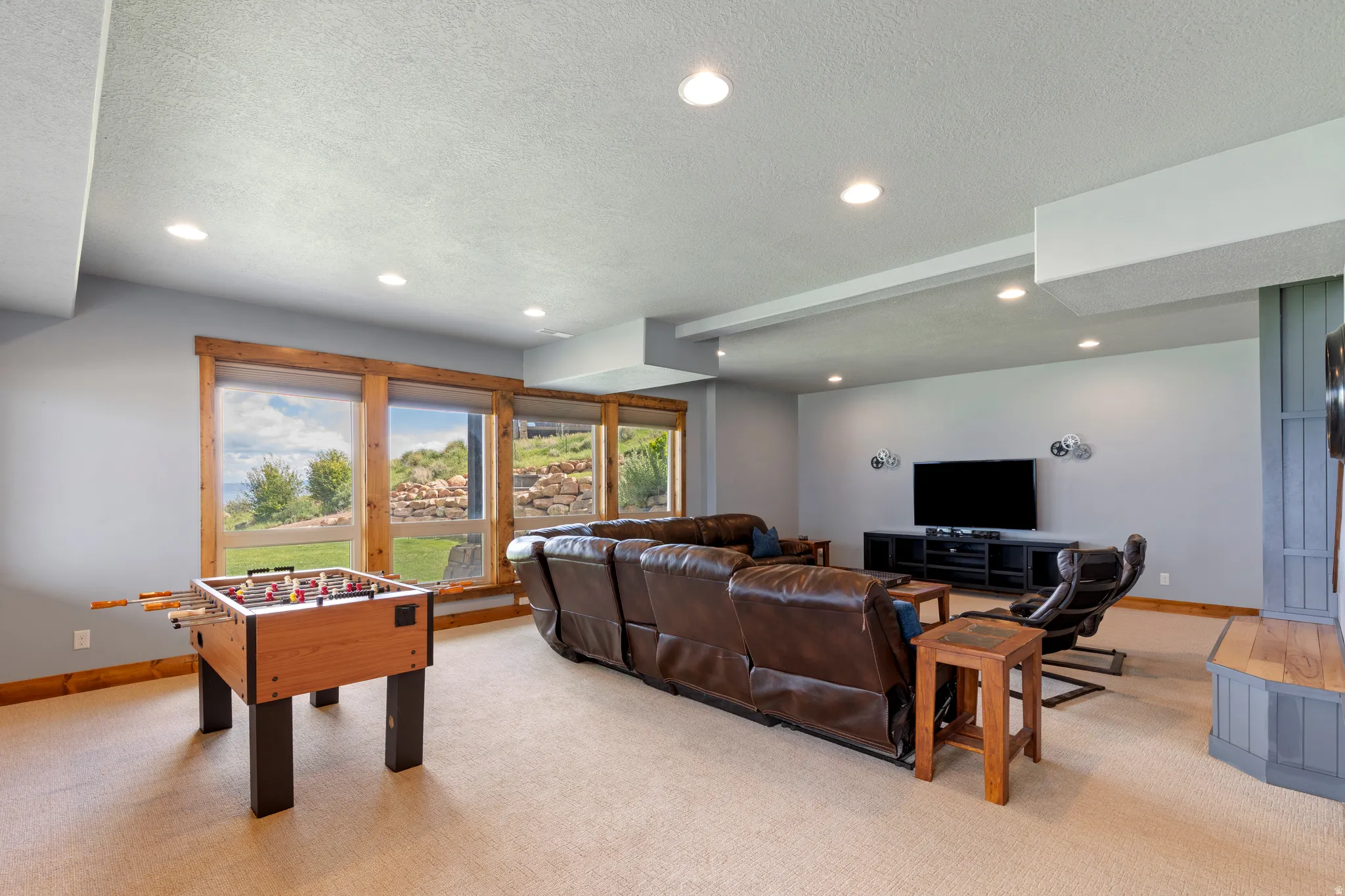 Lower-level recreation space featuring wood-trim windows, recessed lighting, and a built-in entertainment unit with a wood-finish mantel