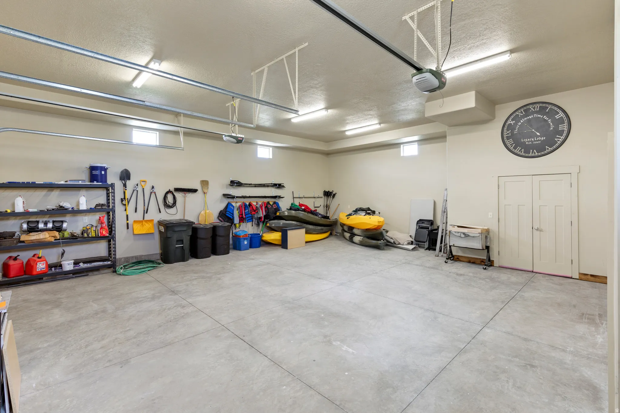 Spacious garage with a durable concrete floor, multiple fluorescent light fixtures, and high ceilings