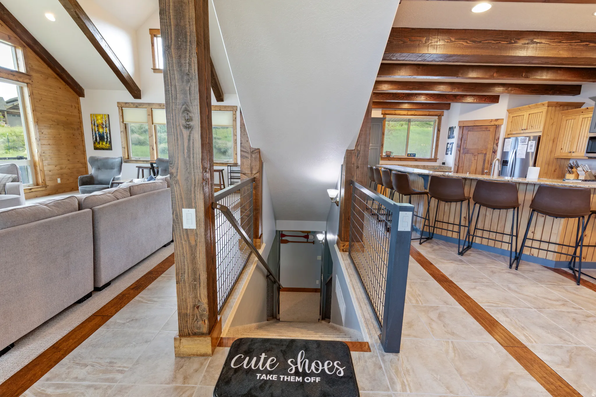 Grand entry featuring tile flooring with wood inlay, leading to a visible lower level