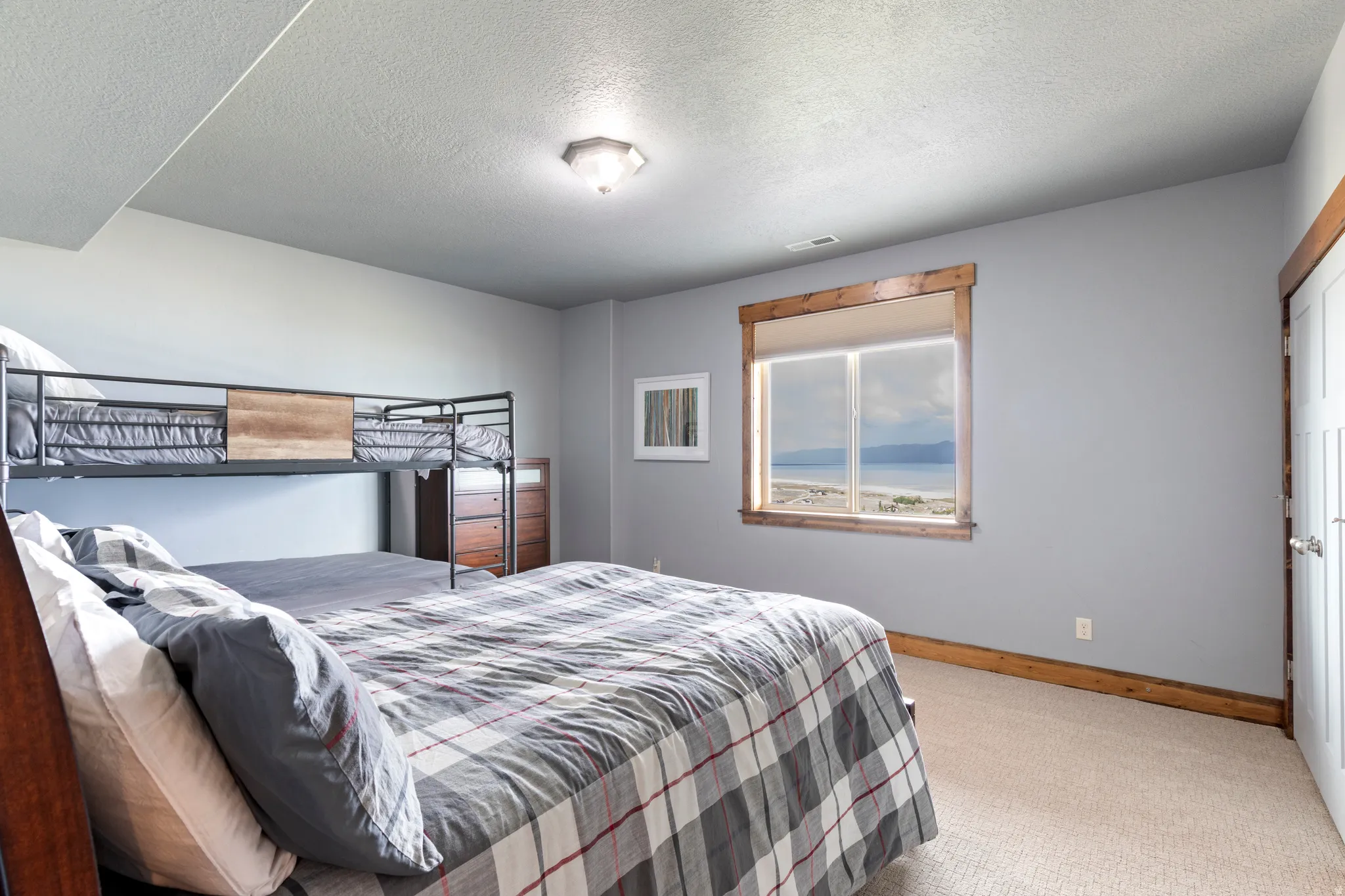 Bedroom featuring carpet flooring, a window with exterior scenery, a white paneled door, and wood trim detailing