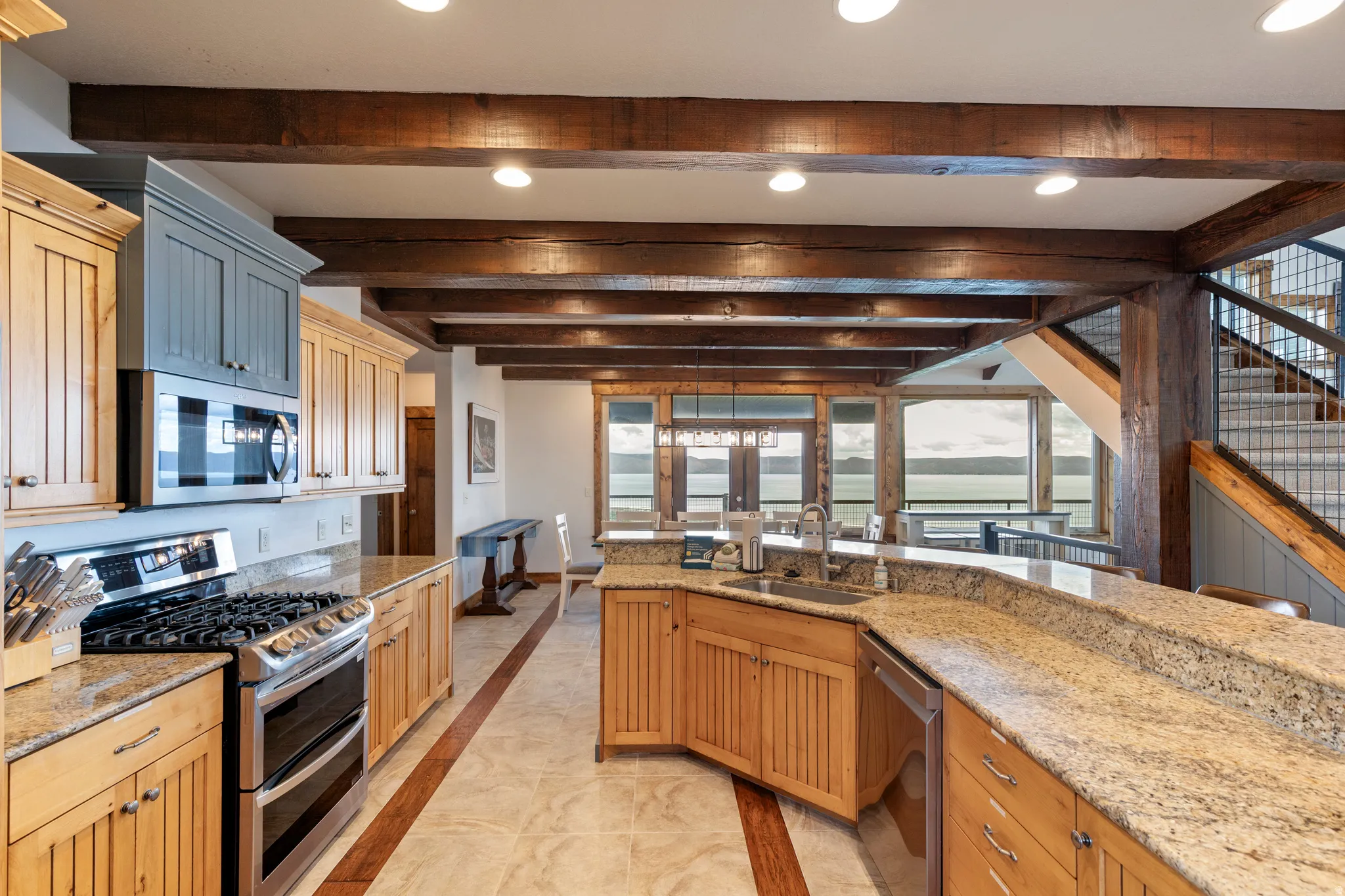 Gourmet kitchen with stainless steel appliances, granite countertops, wood-finish cabinetry, and exposed wood beams