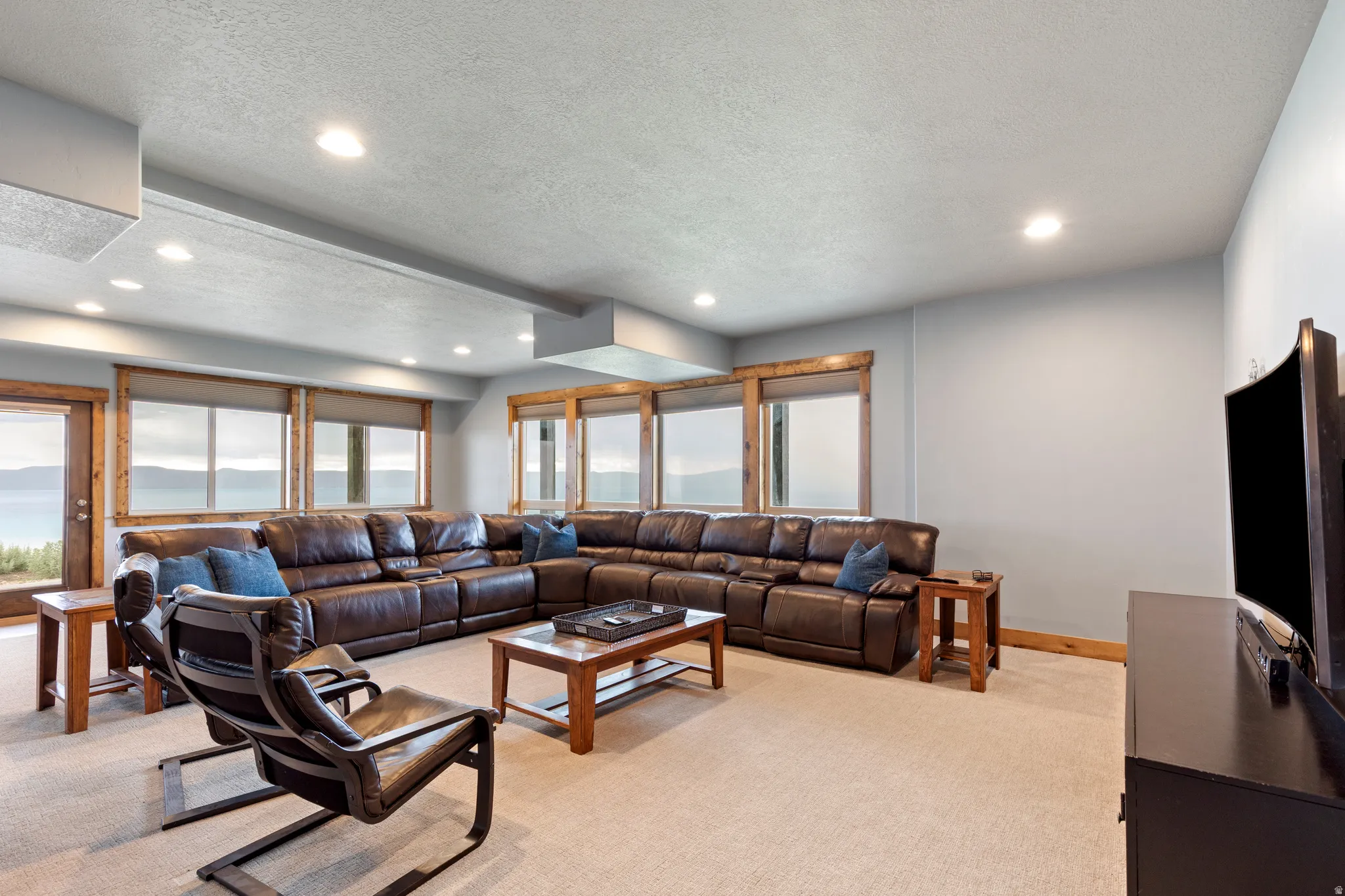 Spacious living area featuring light-toned carpeting and recessed lighting