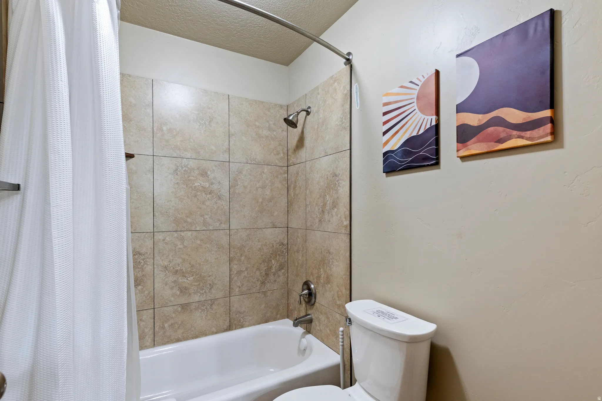 Bathtub and shower combination featuring neutral-toned tile surround with a chrome shower head and faucet