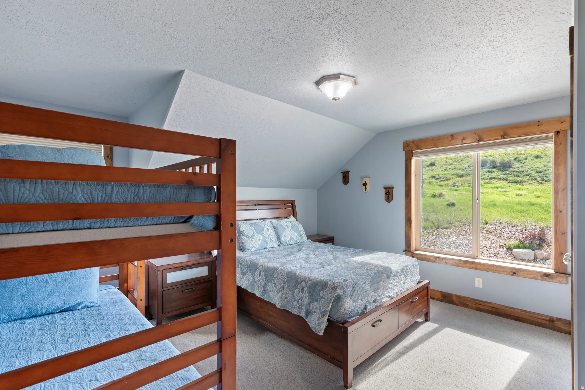 Carpeted bedroom featuring a large picture window with a rustic wood frame, offering expansive outdoor scenery