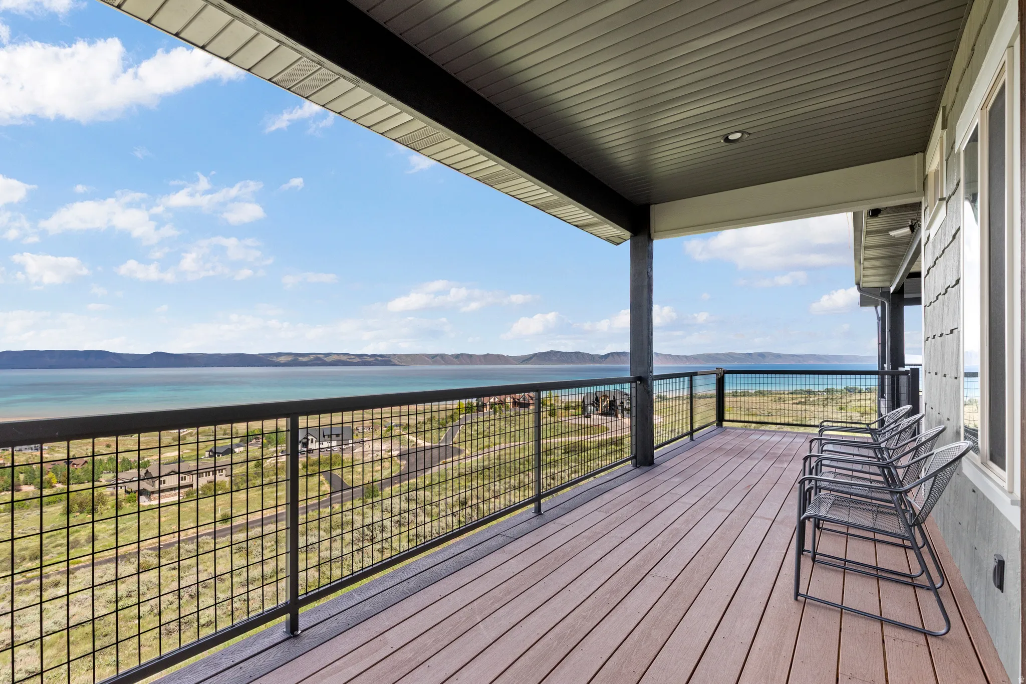 Spacious covered balcony featuring wood-finish decking and a metal grid railing