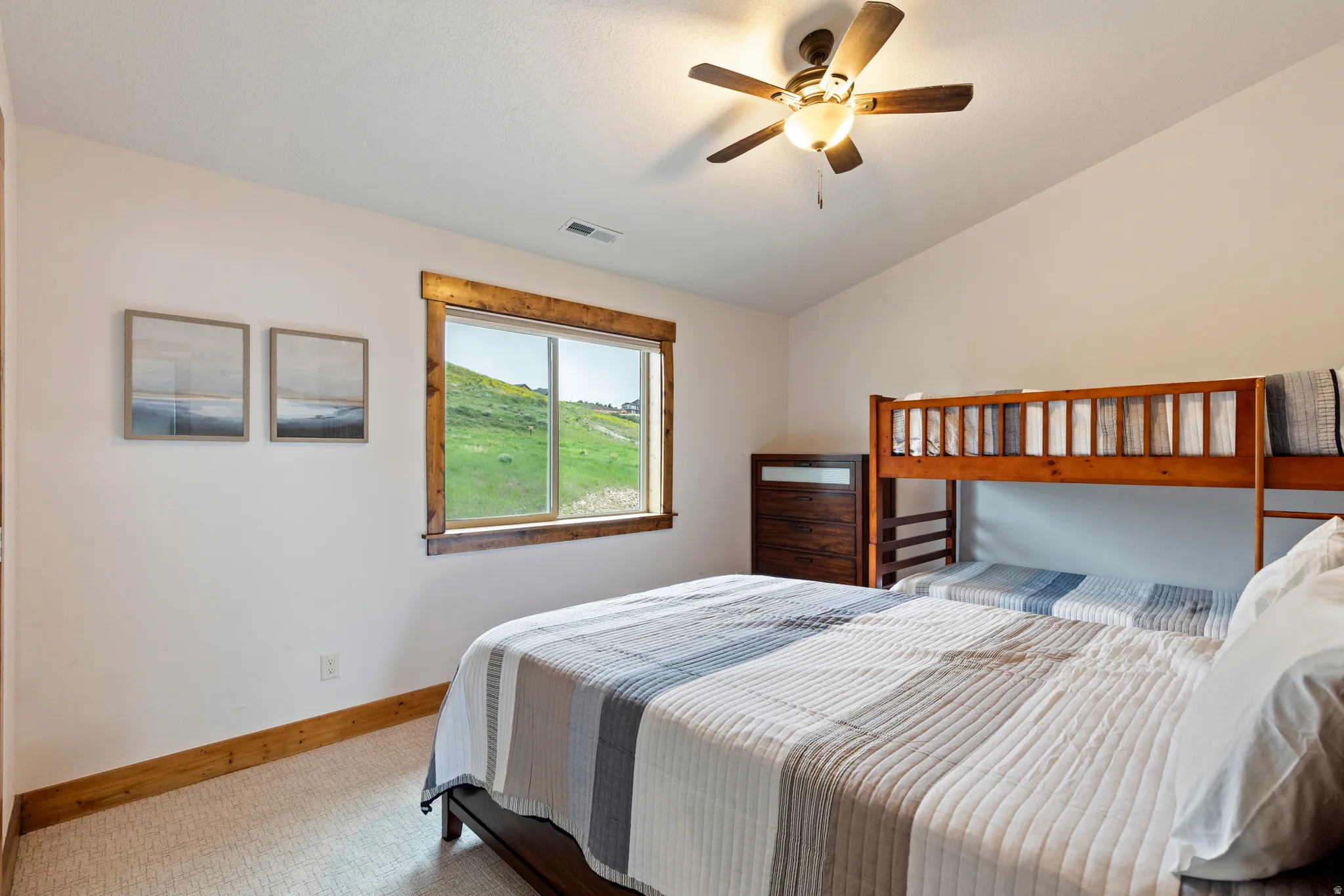 Bedroom with a large window featuring wood trim, textured carpeting, and a ceiling fan with integrated lighting