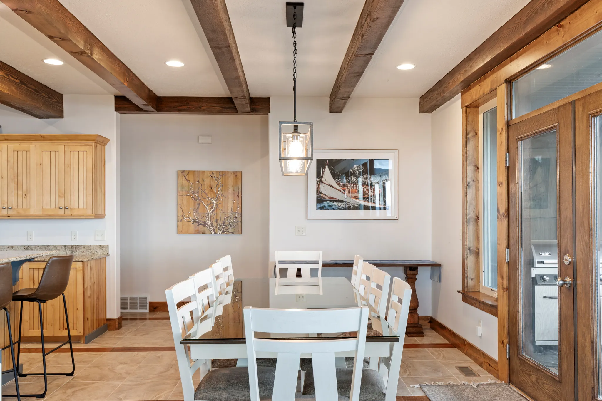 Open concept dining area featuring wood-finish ceiling beams, recessed lighting, a modern pendant light fixture, and wood-finish French doors with integrated side panels