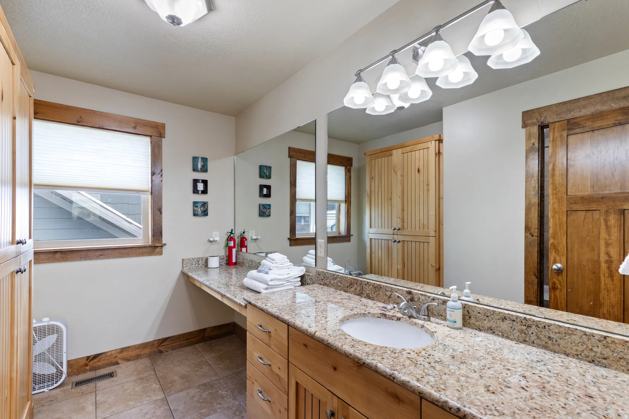 Bathroom featuring a single vanity with an integrated oval sink, a speckled countertop, and wood-finish cabinetry