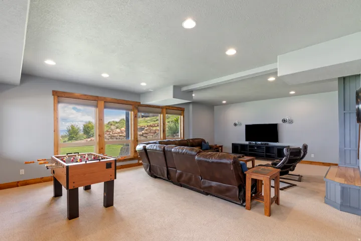 Lower-level recreation space featuring wood-trim windows, recessed lighting, and a built-in entertainment unit with a wood-finish mantel