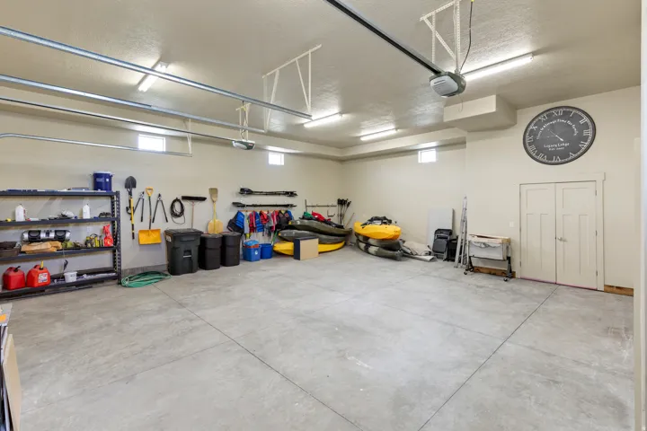 Spacious garage with a durable concrete floor, multiple fluorescent light fixtures, and high ceilings