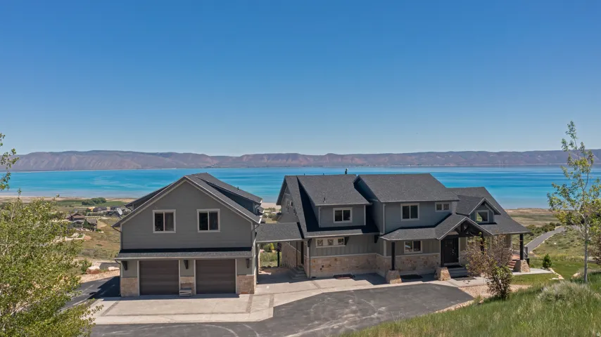 Contemporary two-story residence featuring light gray siding and stone veneer accents