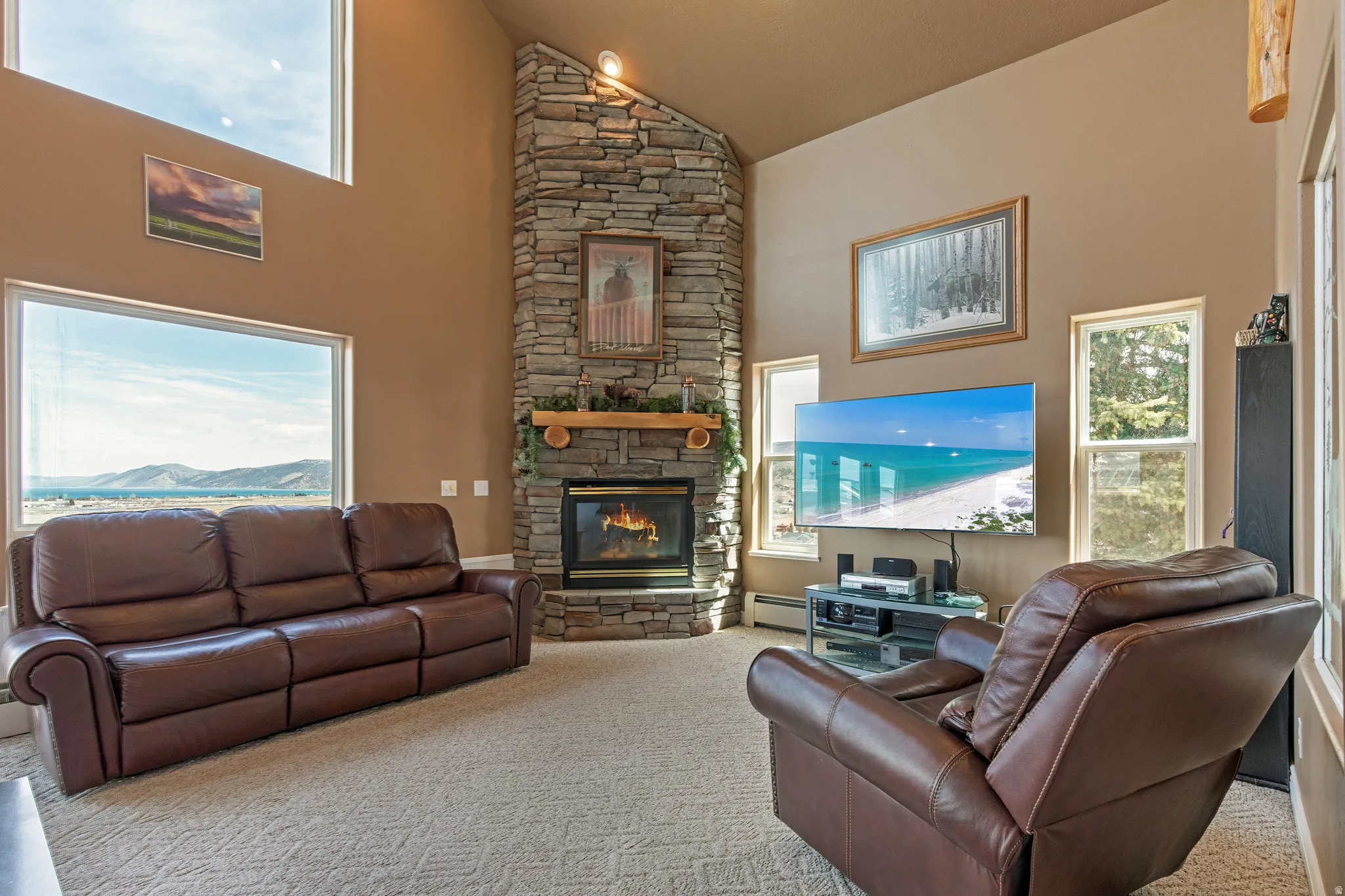 Living area featuring a stone fireplace with a wood mantel, vaulted ceilings, and large picture windows