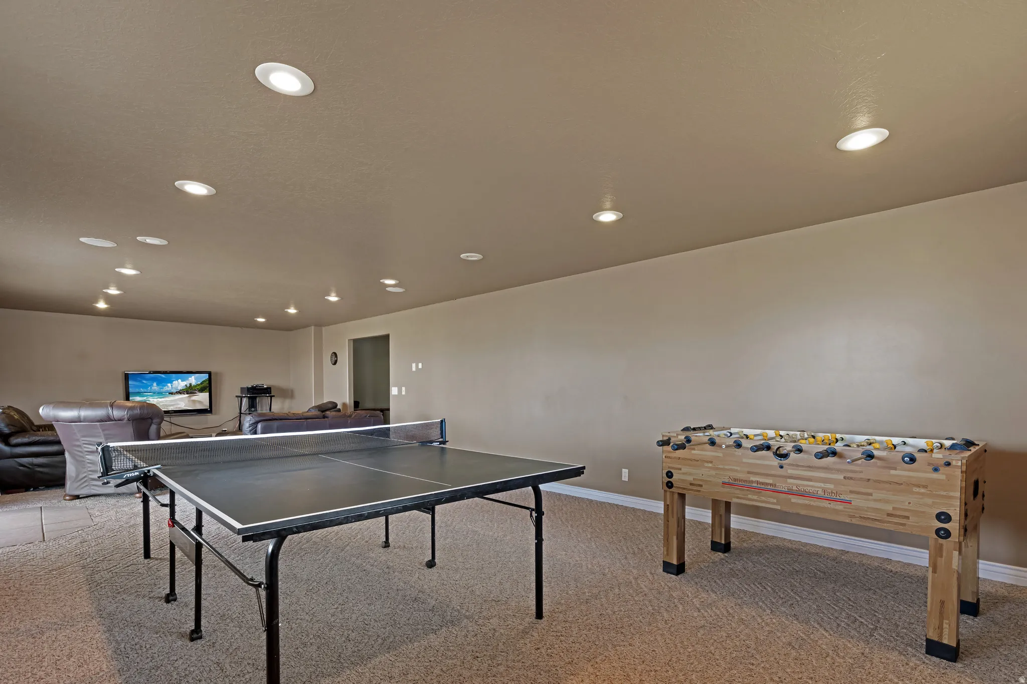 Spacious recreation room featuring recessed lighting, a neutral color palette, and carpeted flooring