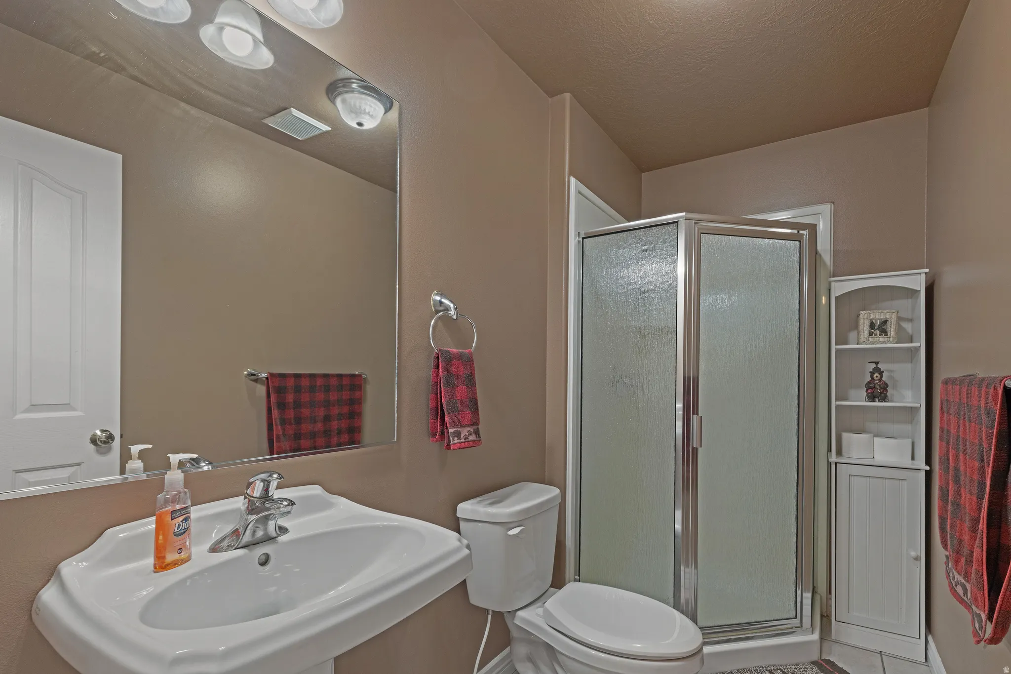 Pedestal sink with chrome faucet, a rectangular mirror, and an overhead vanity light fixture