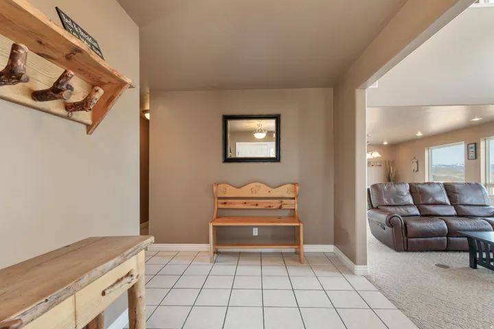 Entryway featuring square white tile flooring, a neutral wall palette, and a framed mirror