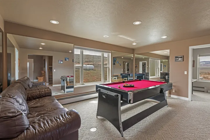 Spacious room featuring broad windows with exterior views, recessed lighting, wall-mounted mirrors, and carpeted flooring
