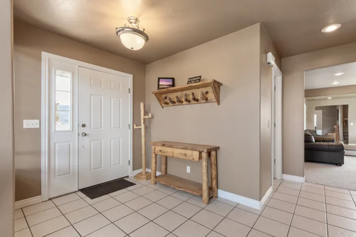 Entryway featuring square tile flooring, a white paneled door with a sidelight, and a semi-flush mount ceiling light fixture