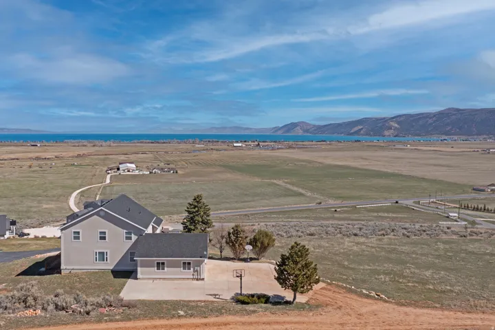 Two-story property with a detached garage, expansive surrounding undeveloped land, and distant water and mountain terrain