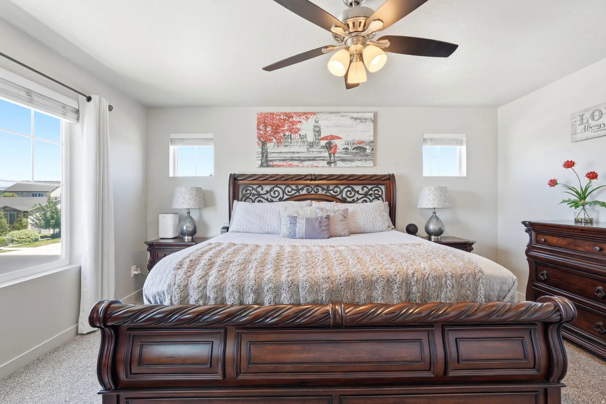 Primary bedroom featuring light gray walls, plush carpet, and a ceiling fan with integrated lighting
