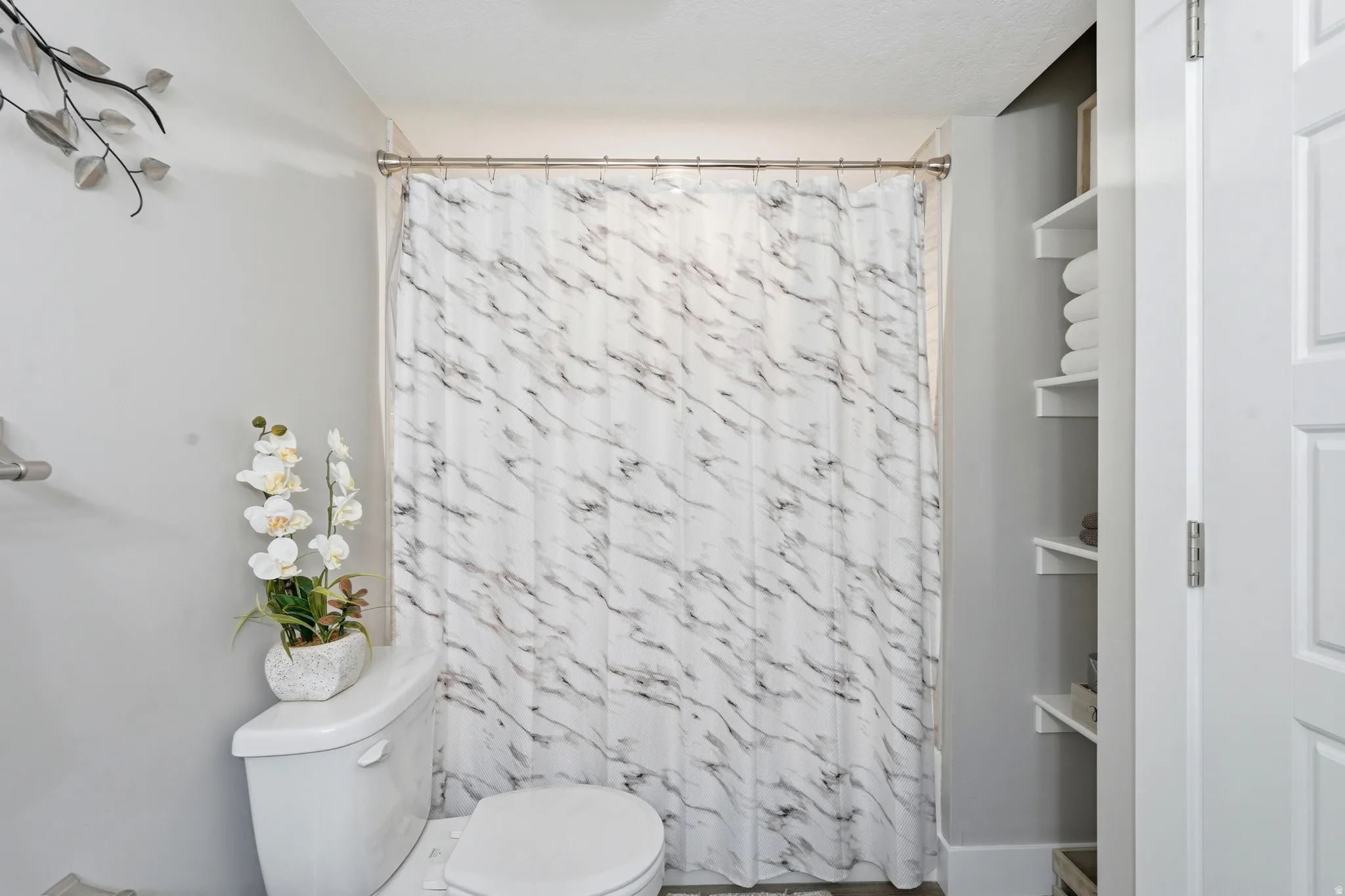 Full-size shower with a white and gray patterned shower curtain