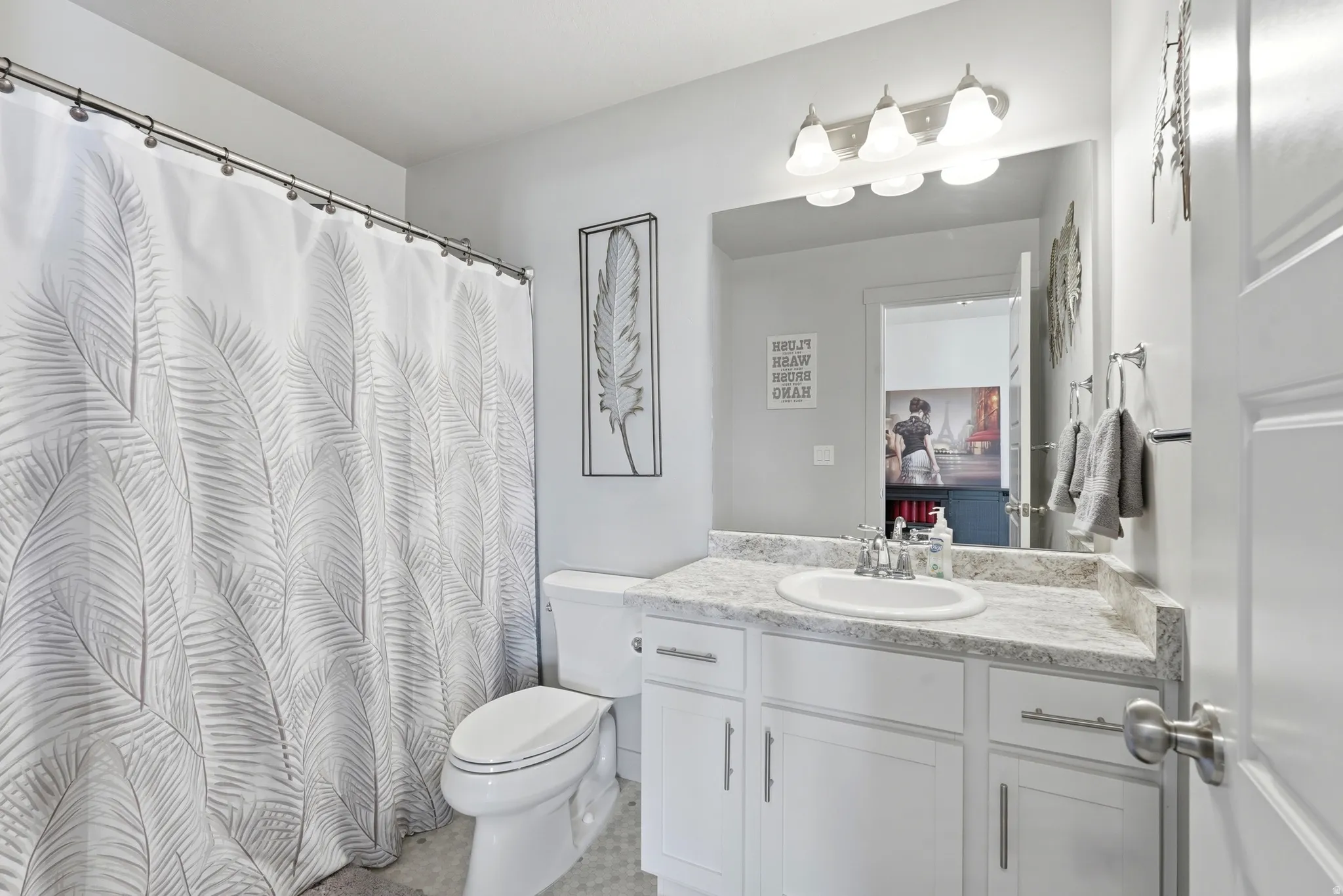 Bathroom featuring a white vanity with a light-toned countertop, a single basin sink, and a mirrored wall
