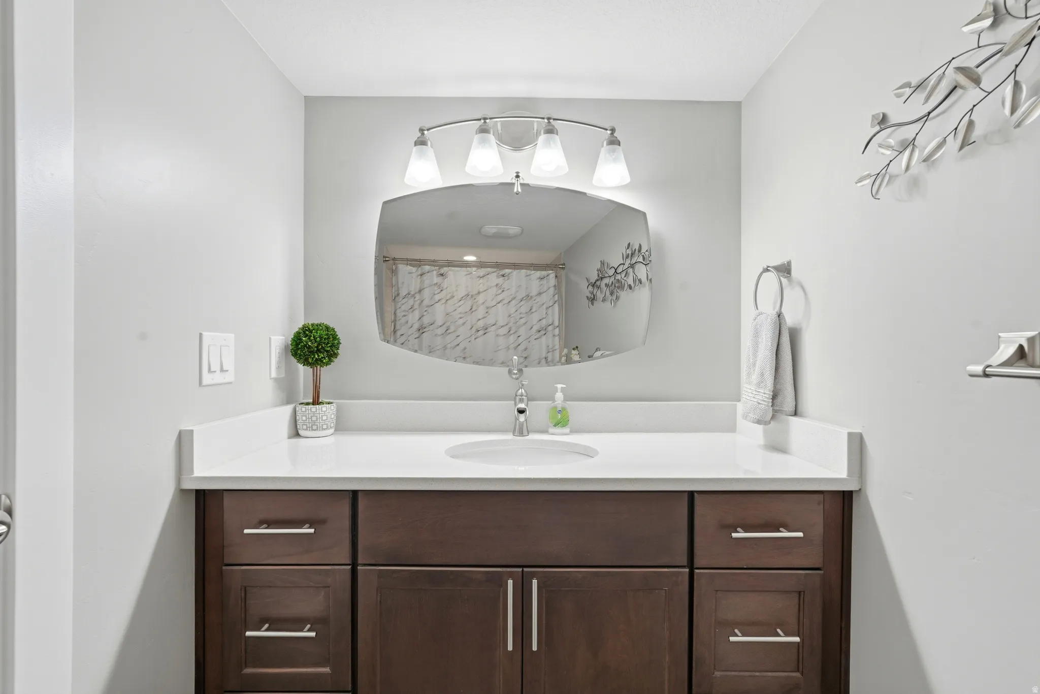 Bathroom vanity featuring a dark wood-finish cabinet with silver hardware, quartz countertop, and an undermount sink