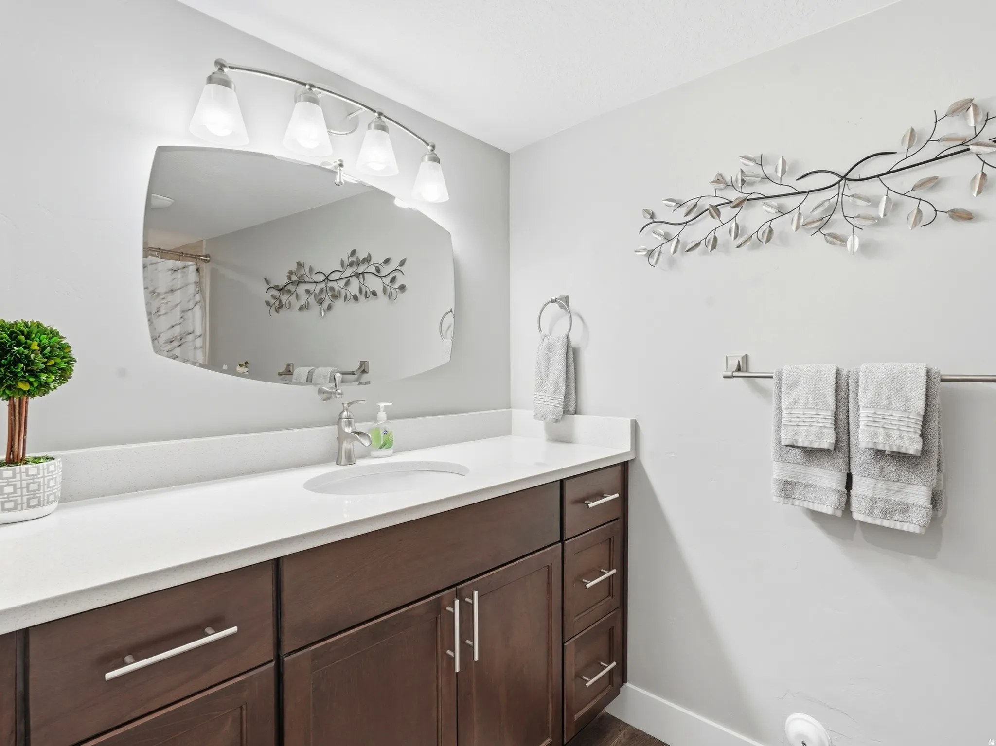 Bathroom vanity featuring dark wood-finish cabinetry, a white countertop, and a single undermount sink