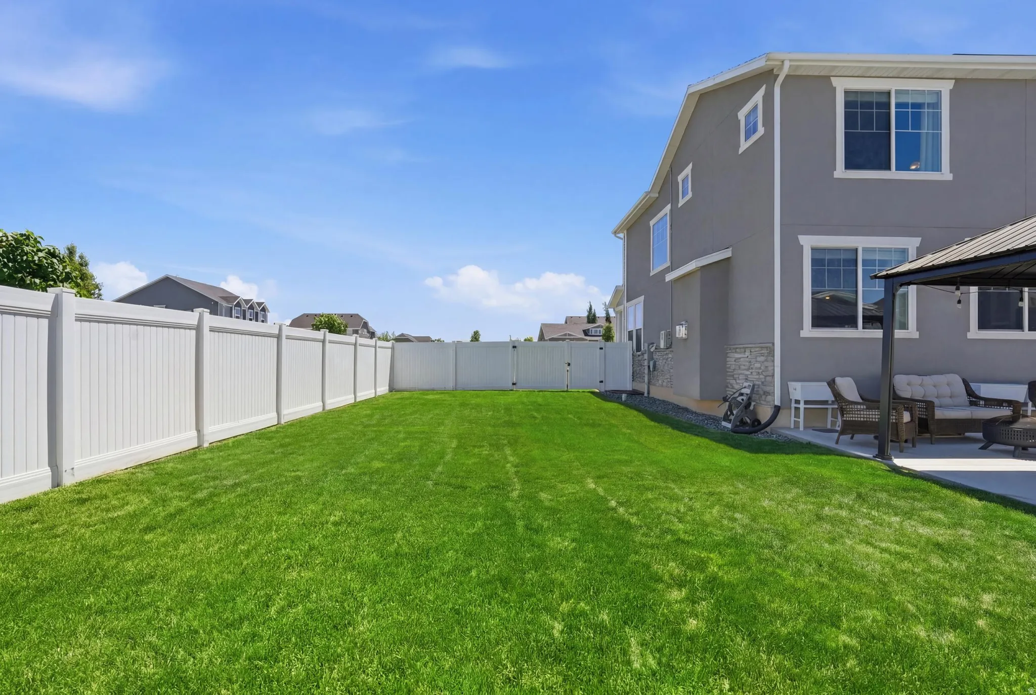Expansive backyard featuring a manicured lawn, full privacy fencing, and a concrete patio