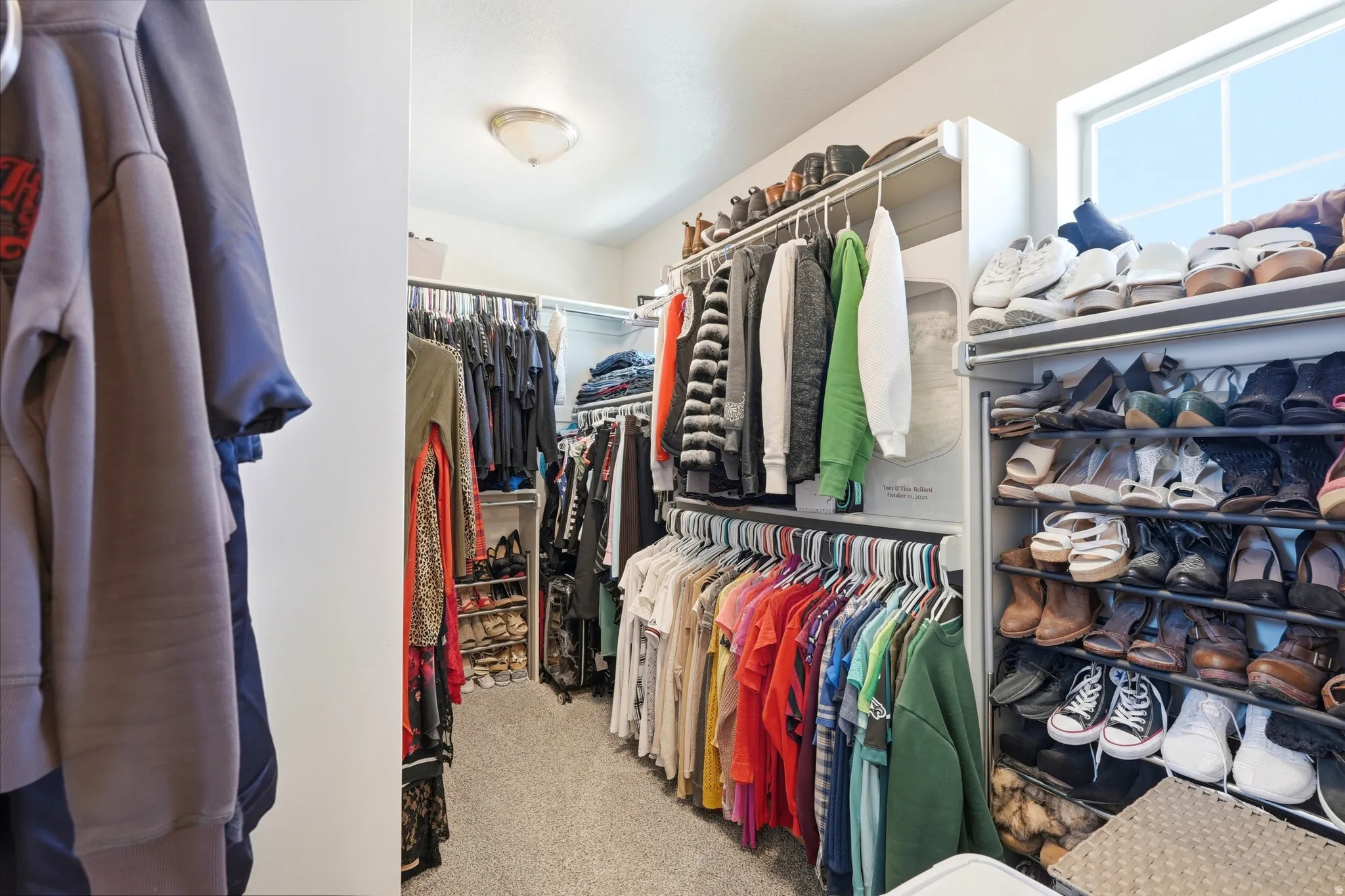 Primary walk-in closet featuring an organizational system with multiple hanging rods and shelving
