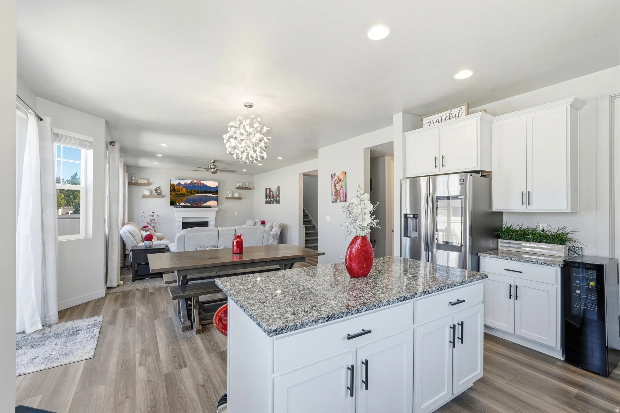 Modern kitchen featuring white cabinetry, stainless steel refrigerator, and granite countertops on the island and perimeter