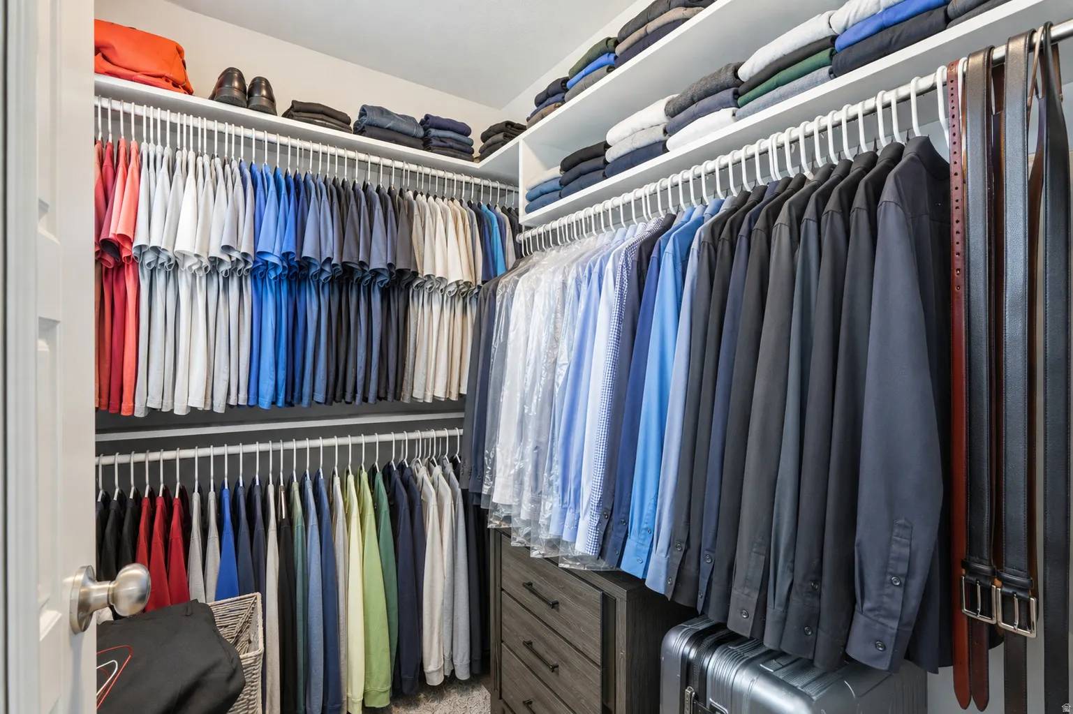 Walk-in closet featuring built-in shelving and multiple hanging rods