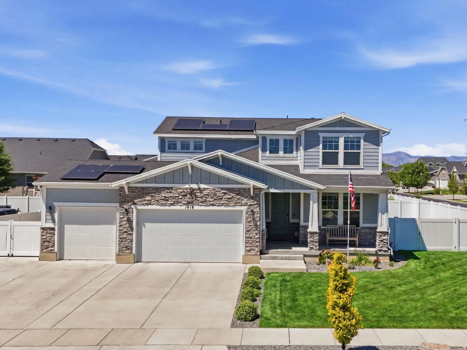 Two-story residence featuring a combination of stone and siding facade, a two-car garage, and solar panels on the roof