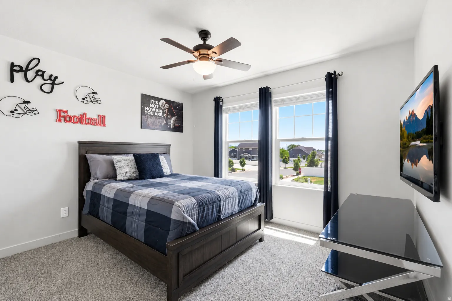 Bedroom featuring two large windows, a ceiling fan with integrated lighting, and light carpeting