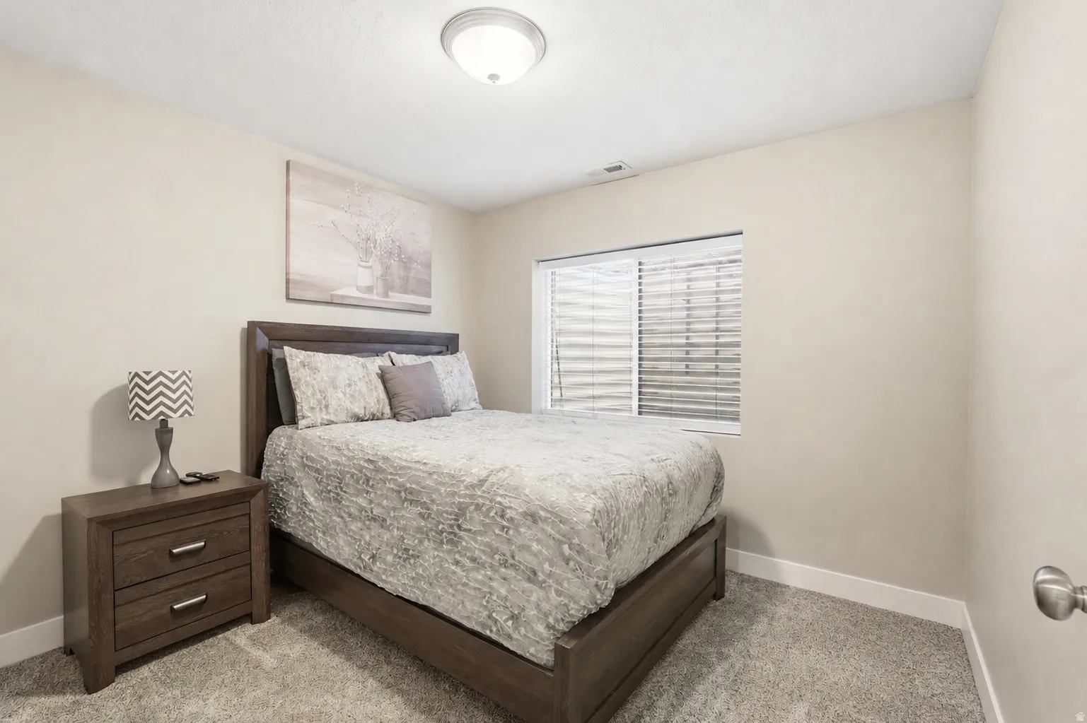 Neutral tone walls and carpeting create a cohesive bedroom environment