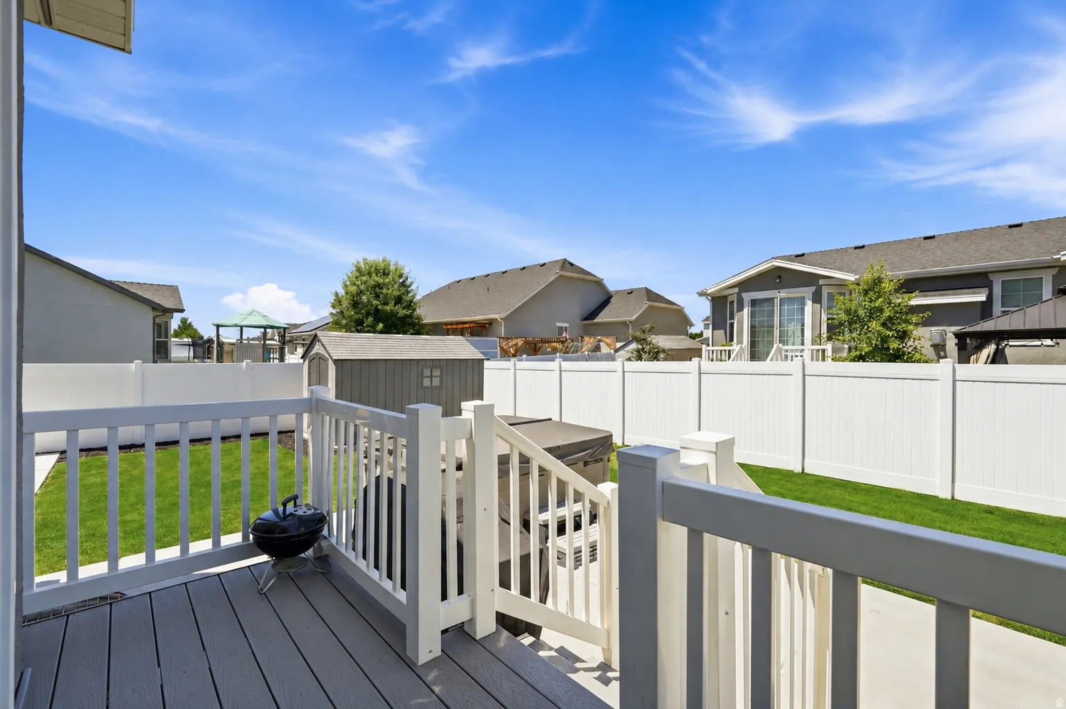 Spacious backyard featuring a composite deck, white privacy fencing, and a storage shed