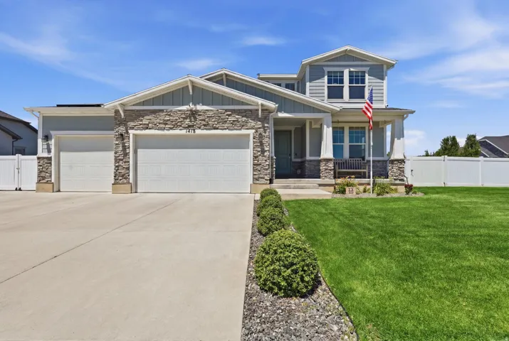 Two-story residence featuring light blue siding with stone accents, a multi-car garage, and a concrete driveway