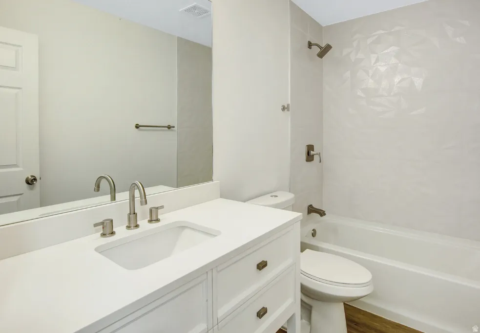 Bathroom featuring a white vanity with integrated sink, brushed nickel hardware, and a framed mirror