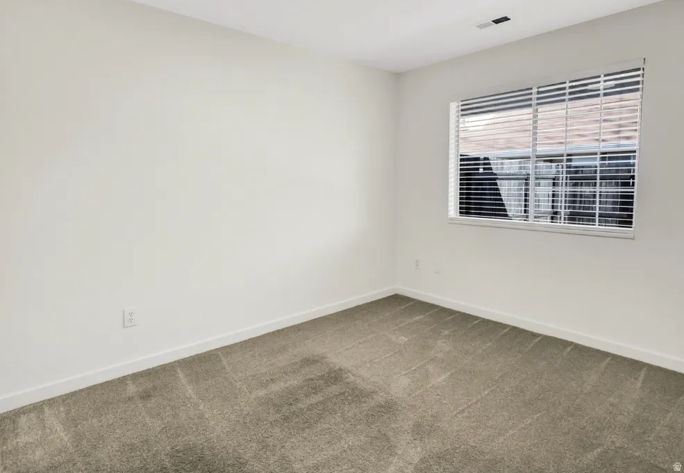 Bright room featuring neutral-toned walls, a window with horizontal blinds, and clean carpeting
