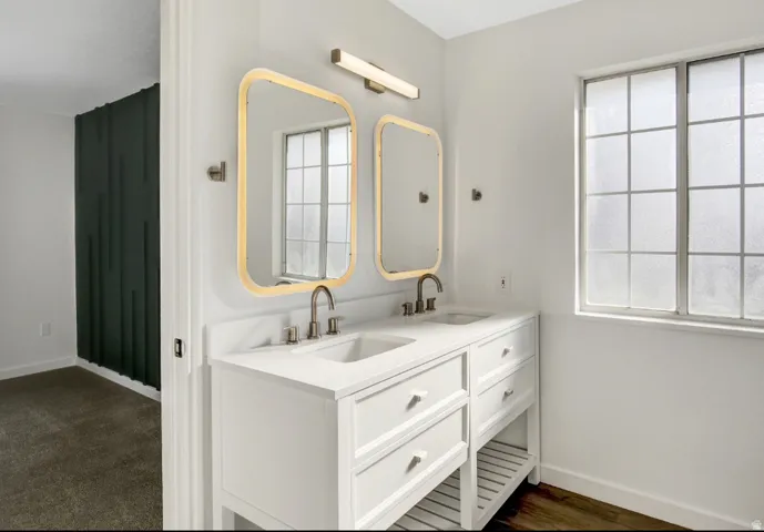Double vanity with white cabinetry and integrated sinks, brushed nickel fixtures, and illuminated rectangular mirrors