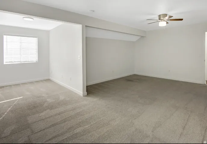Spacious carpeted interior featuring a ceiling fan, recessed lighting, and window blinds