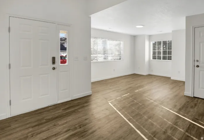 Entryway featuring a paneled door with an adjacent sidelight, wood-finish flooring, white baseboards, and white walls