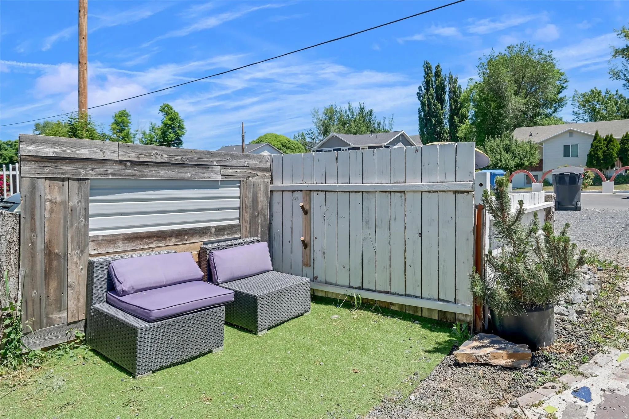 Private outdoor area featuring artificial turf, a wood and corrugated metal fence, and a white painted wood fence