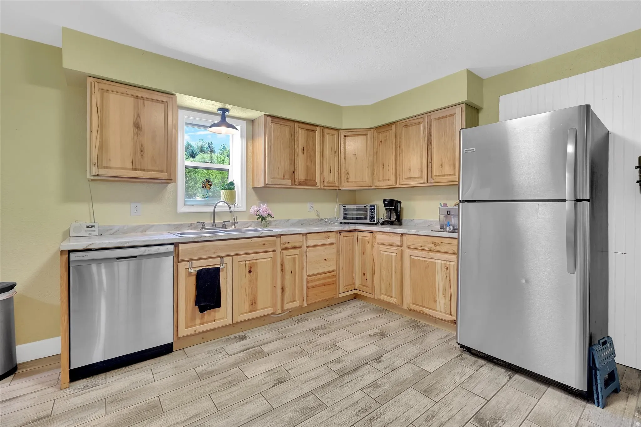 Kitchen featuring natural wood cabinetry, light-toned countertops, and wood-finish tile flooring
