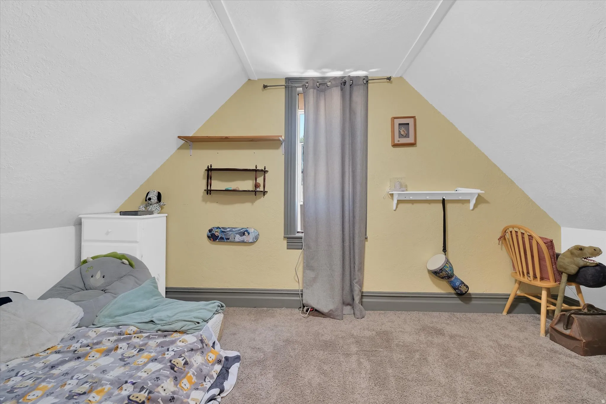 Attic room featuring a single window, sloped ceilings, and neutral-toned carpeting