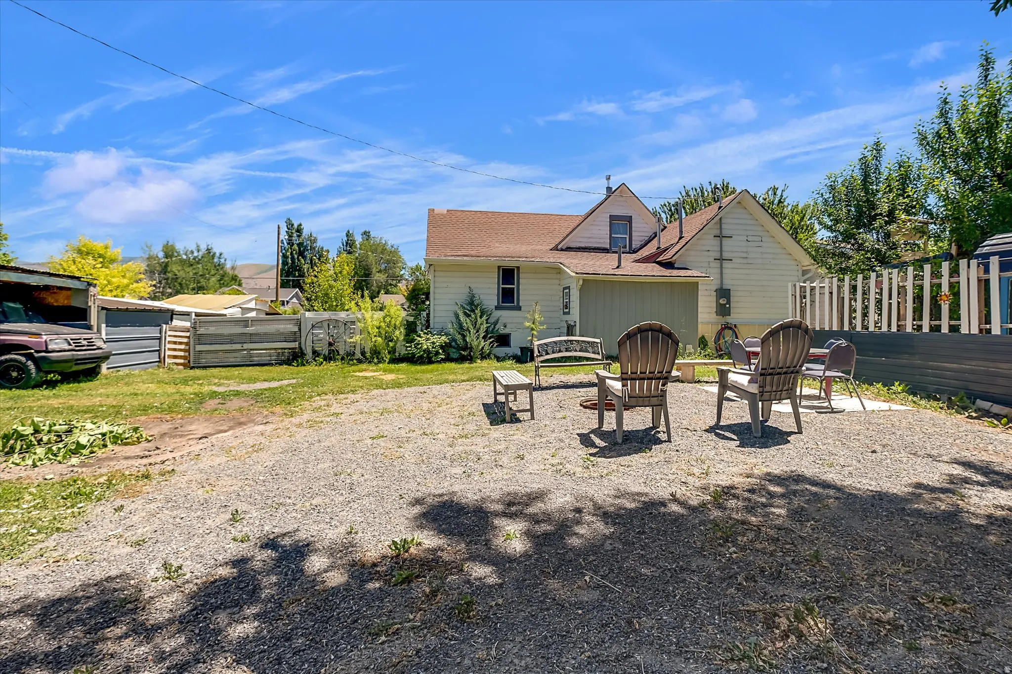 Expansive gravel patio area with a built-in fire pit feature, bordered by a privacy fence and mature landscaping